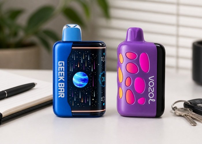 Blue Geek Bar Pulse X2 and purple VOZOL Rave 50K standing side by side on an adult desk