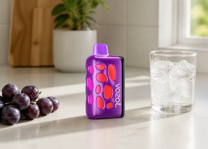 Purple VOZOL Rave 50K Grape Ice beside grapes and ice water on an adult kitchen counter