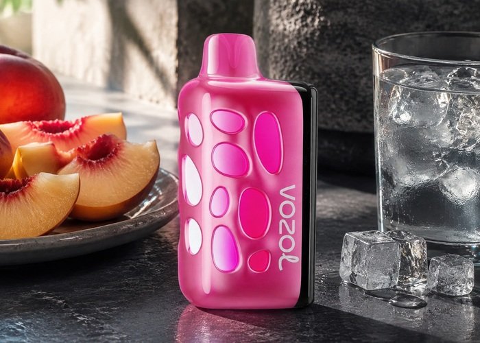Pink VOZOL Rave 50K Peach Ice beside peach slices and ice water on an adult counter